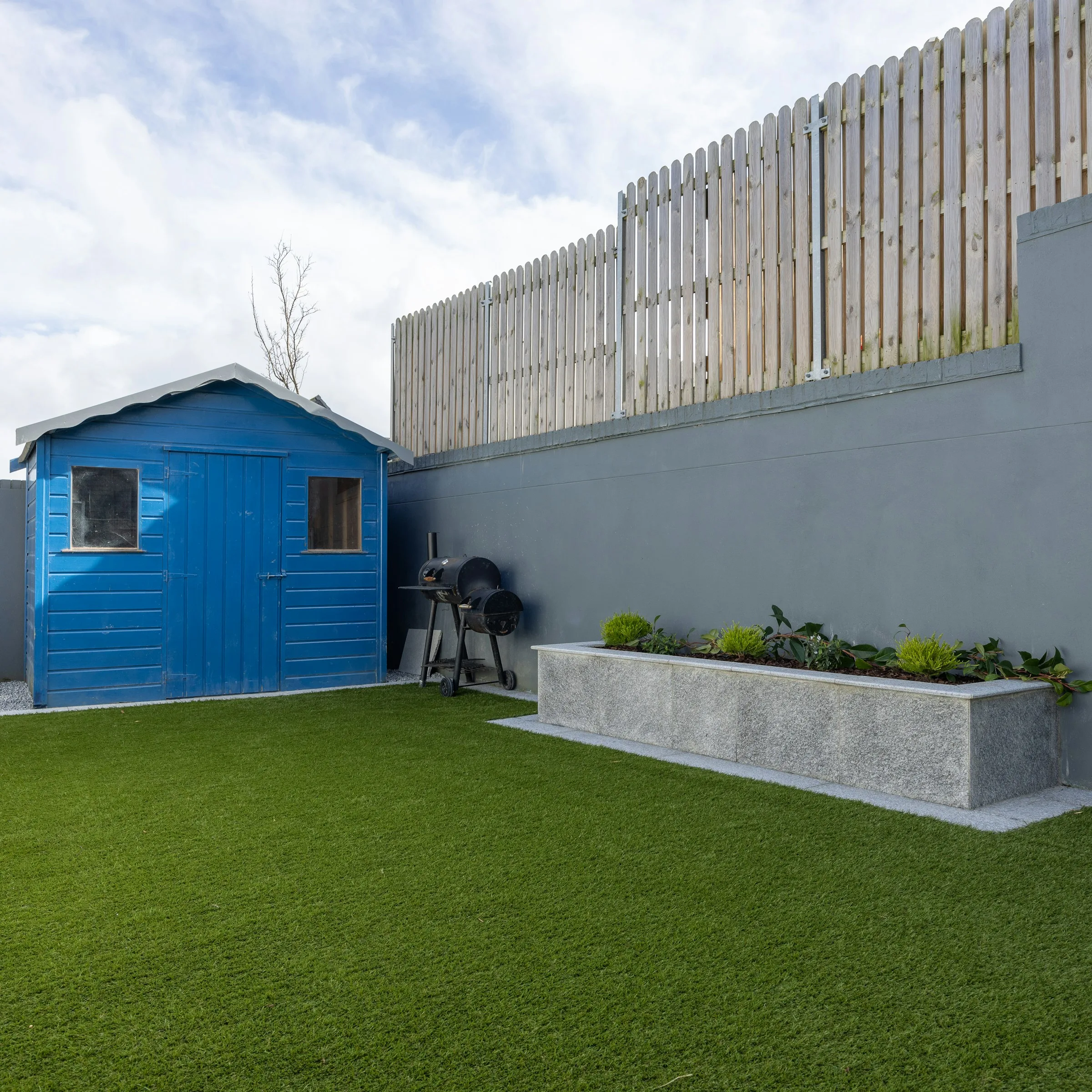 Artificial lawn beside a garden shed and raised planter