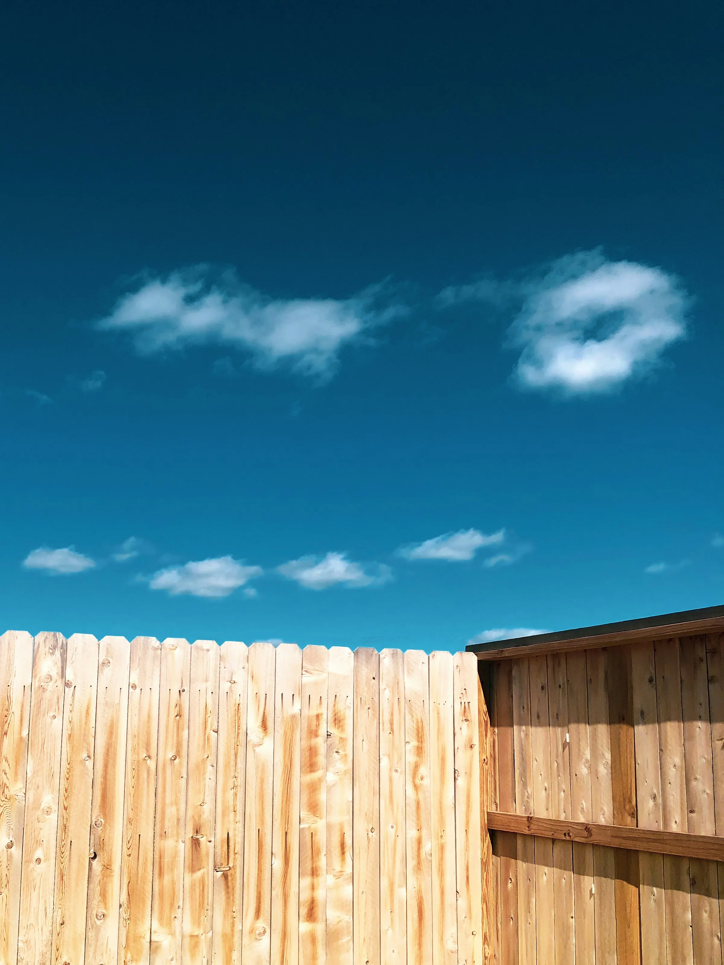 New residential wood fence under a clear sky
