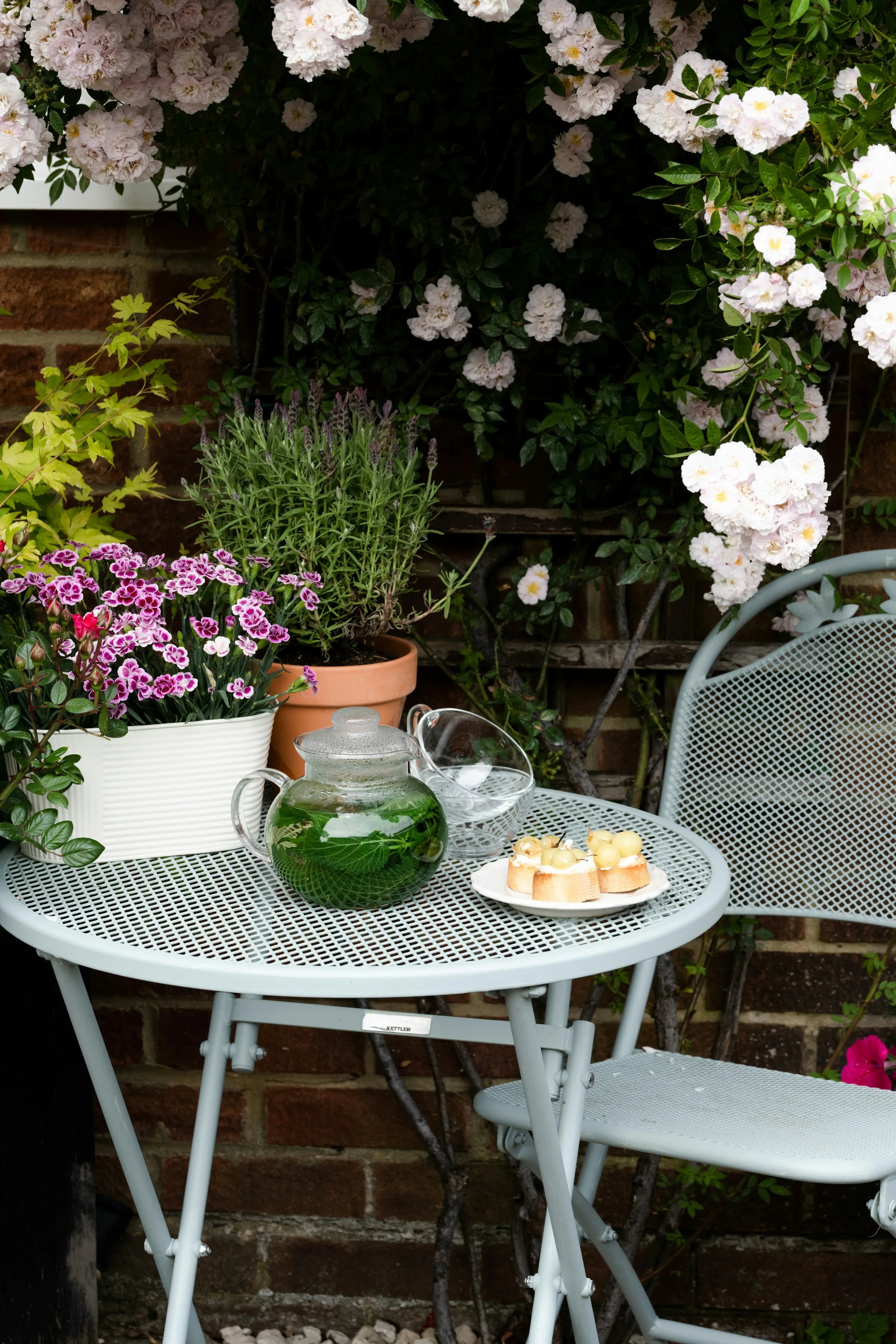 Outdoor patio table surrounded by garden flowers and greenery