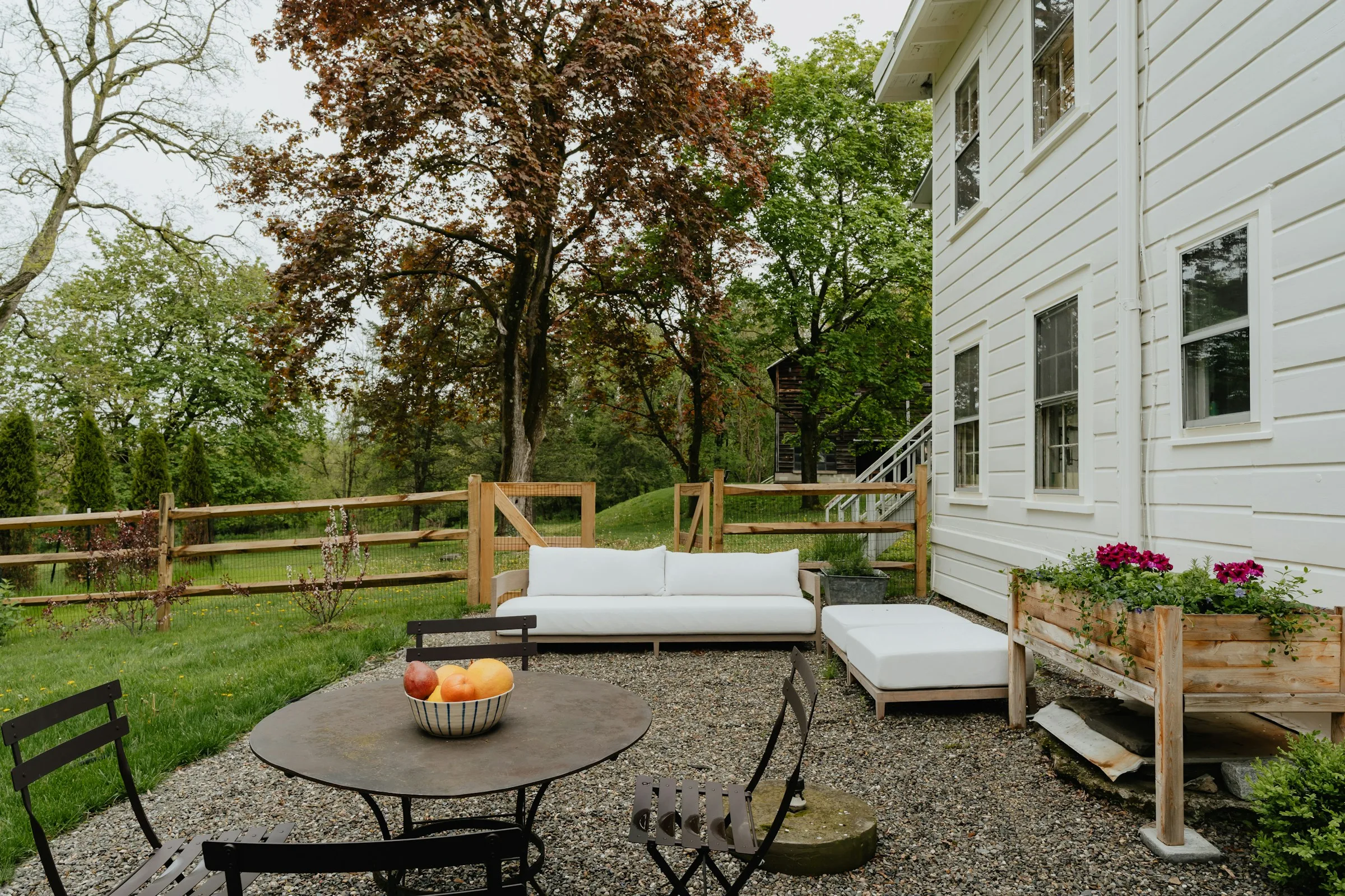 Landscaped backyard patio with a fire pit, gravel, and lawn