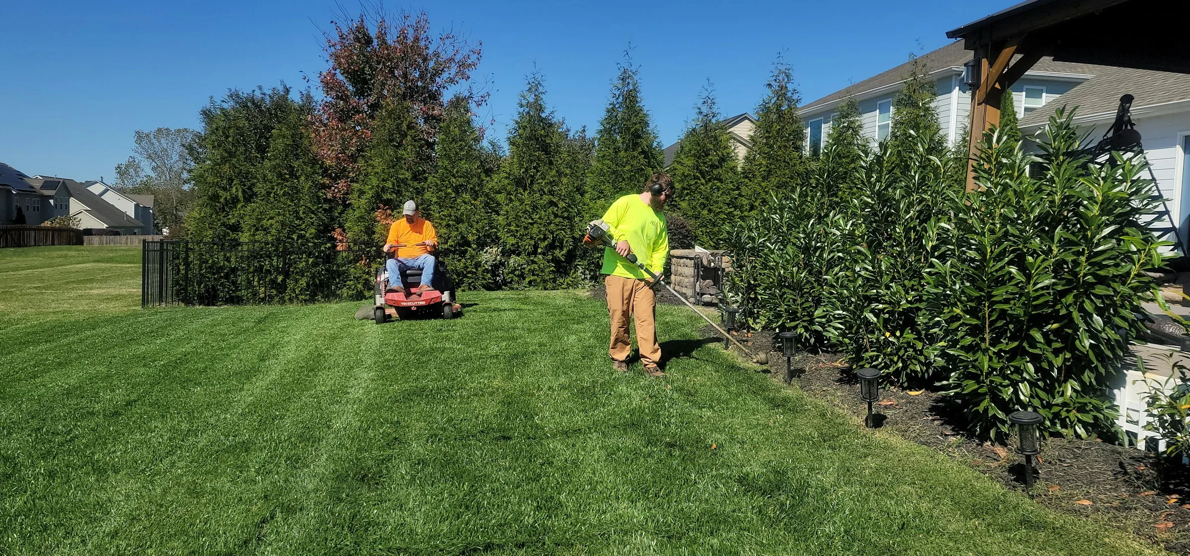 Landscape maintenance crew mowing a large green lawn