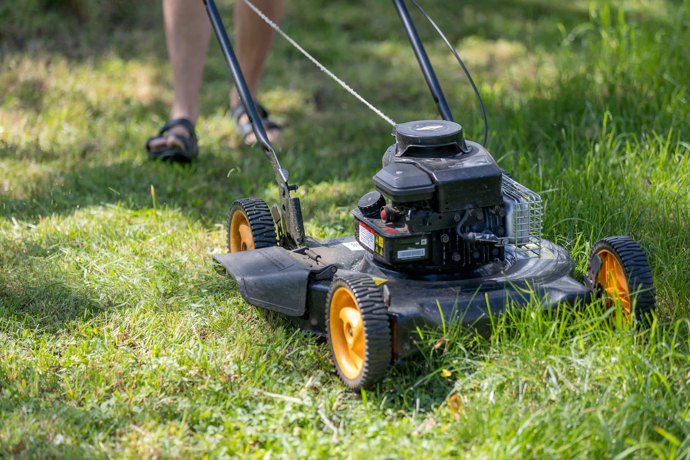 Push mower cutting a neatly maintained lawn