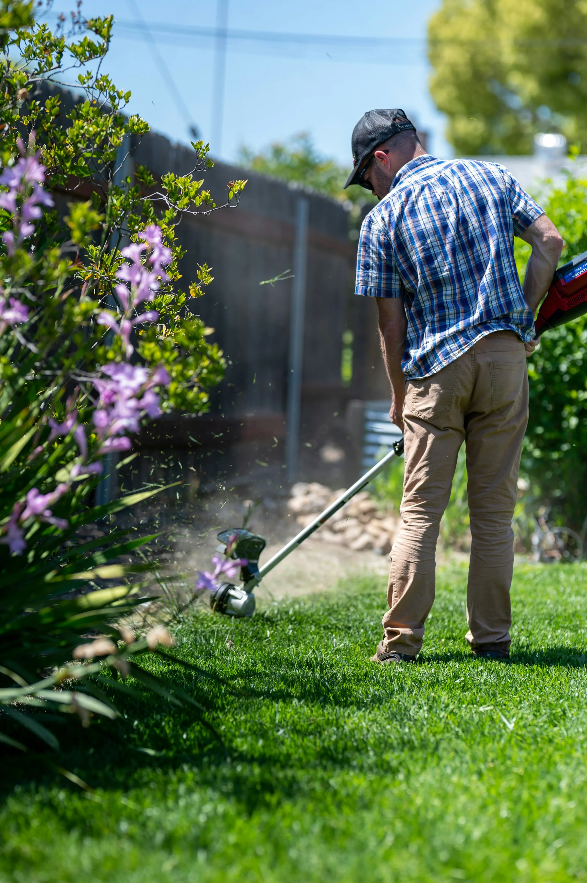 Landscaper trimming the edge of a green lawn